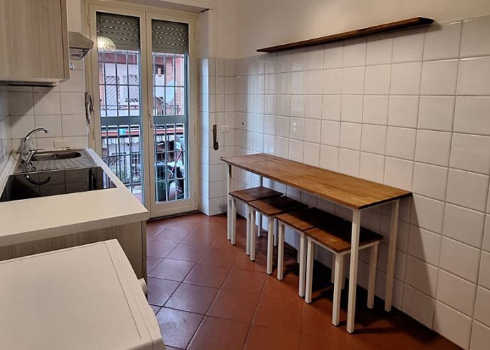 Zona pranzo della cucina con tavolo in legno e accesso al balcone