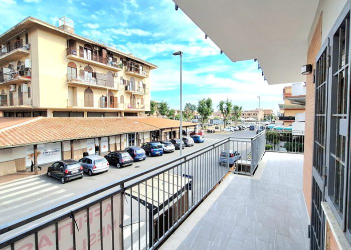 vista dal balcone dell’appartamento terrazza del mare su strada con negozi, parcheggio e palazzi